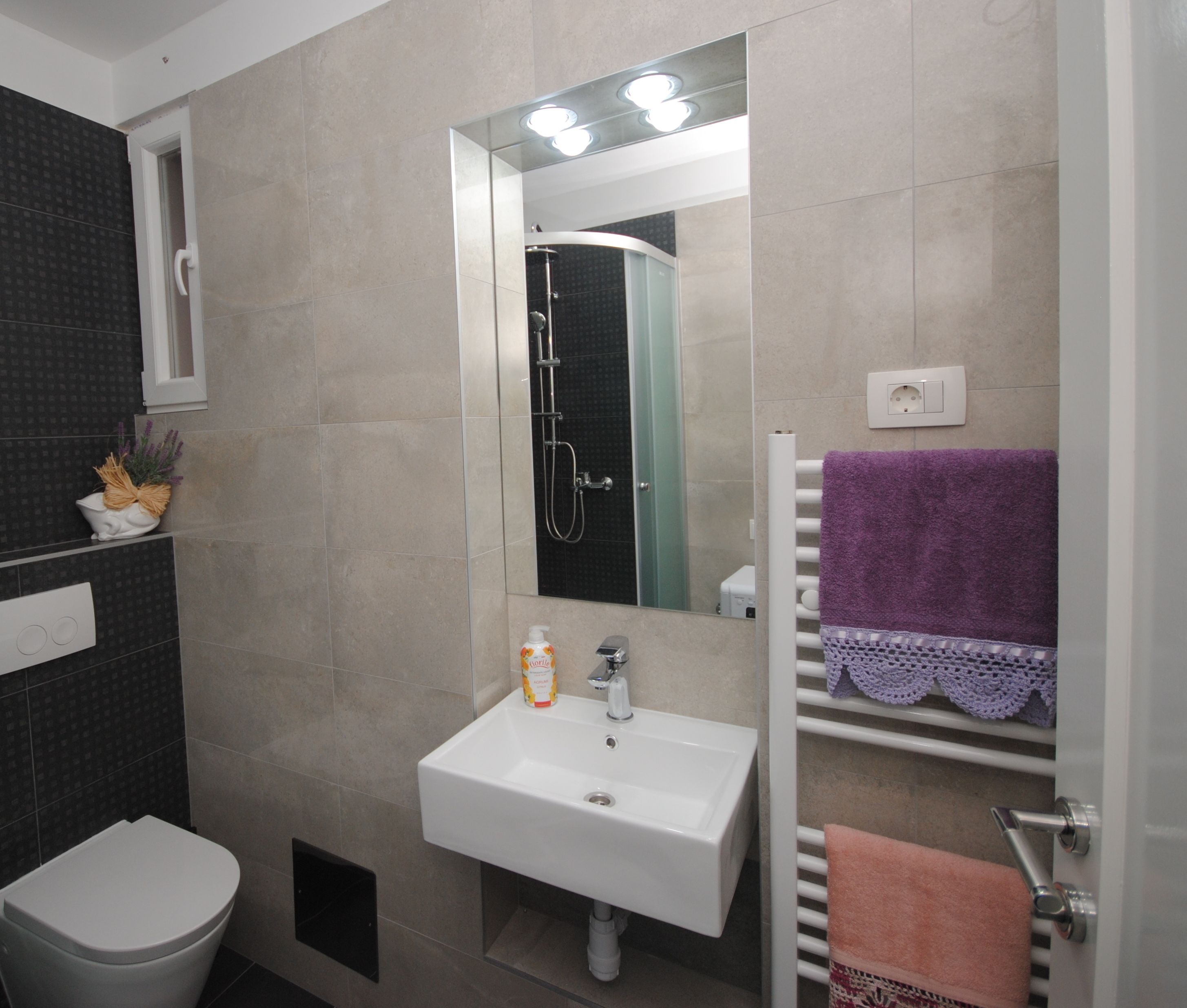A bathroom with a white sink, a mirror, a shower, and a toilet.