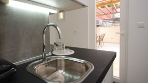 A modern kitchen with a stainless steel sink, a faucet, and a countertop. There is a window with a view of an outdoor patio area.