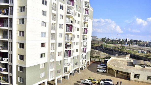 A multi-story residential building with balconies, a parking area, and a view of the surrounding area. - Cafri Homestay (Syokimau)
