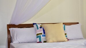 A bed with a wooden headboard, white bedding, and a canopy. - Cafri Homestay (Syokimau)