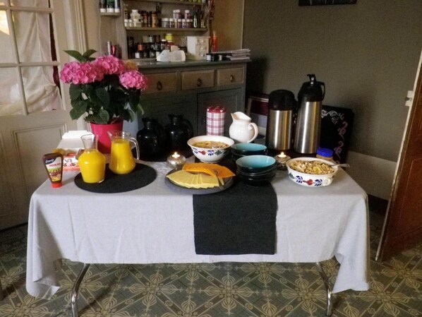 A breakfast table with various dishes, condiments, and a vase of flowers.