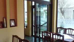 A restaurant with wooden chairs and tables, a glass door leading outside, and framed pictures on the wall. - Hotel Sofia (Pomorie)