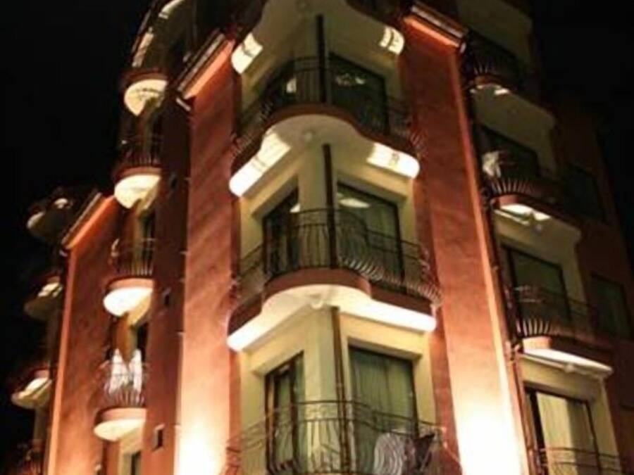 A multi-story hotel with balconies and illuminated windows.