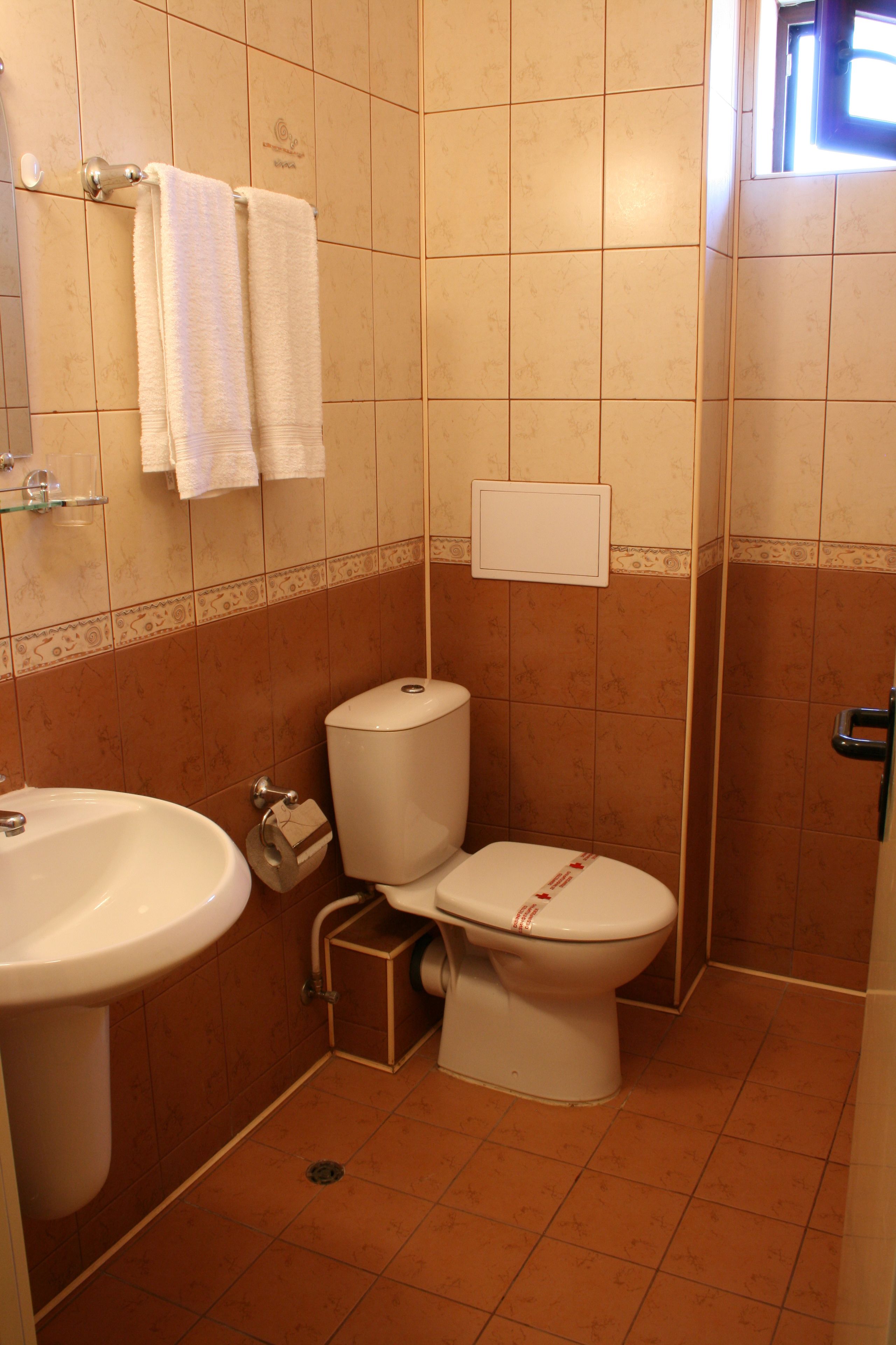 Une petite salle de bain avec des toilettes, un lavabo et deux serviettes accrochées au mur.