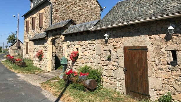 Un bâtiment en pierre avec un toit en pente, une porte en bois et une petite fenêtre.