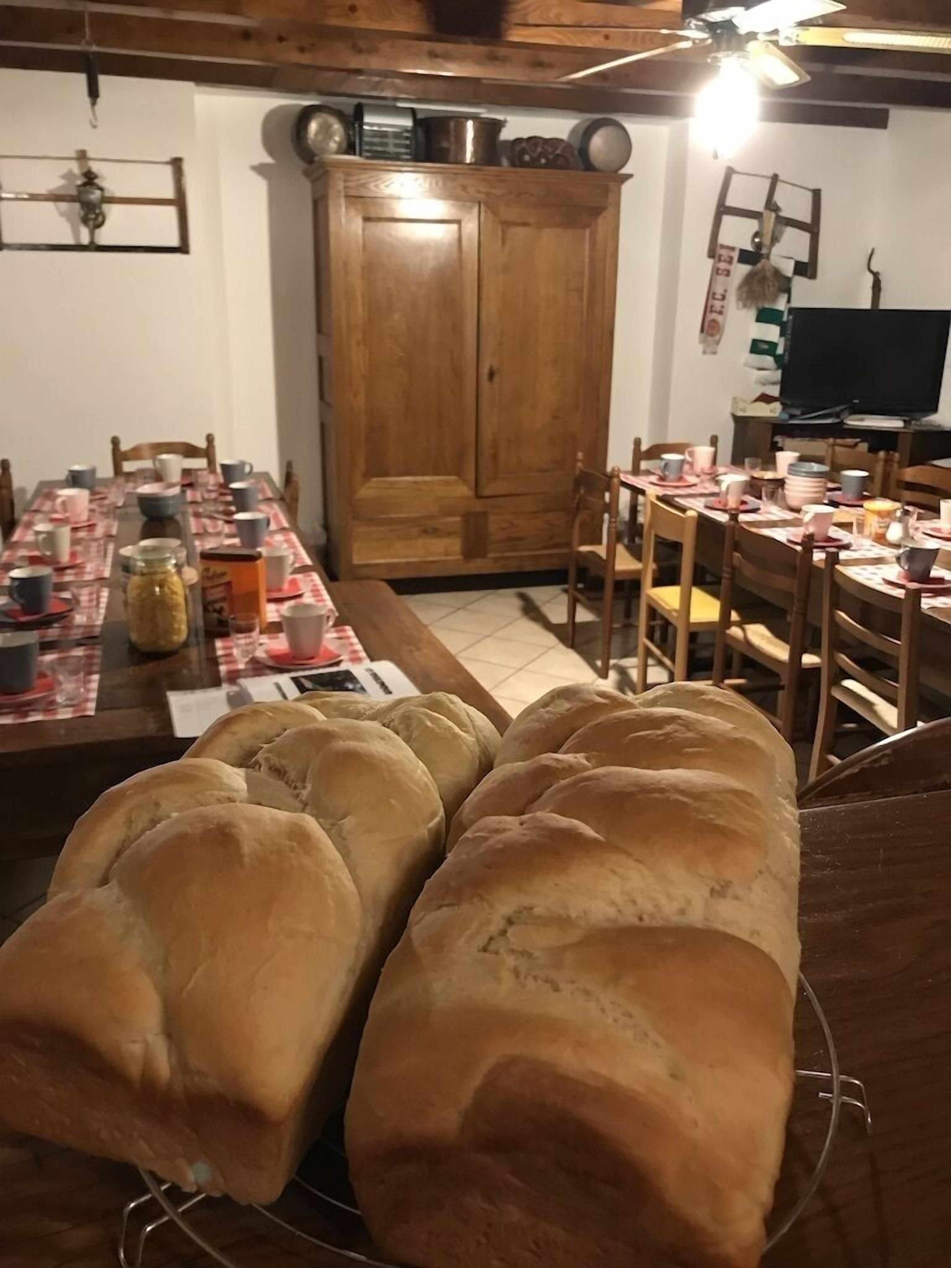 Un comedor con una mesa de madera dispuesta para una comida, un aparador de madera y un televisor al fondo.