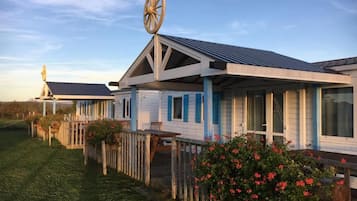 A row of cabins with a distinctive wheel feature on the roof, wooden decks, and a grassy area in front.