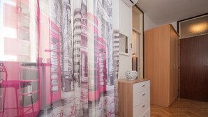 Ein Zimmer mit einem Holfischschrank, einem weißen Schrank und einem rosa Sessel.