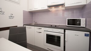 Eine moderne Küche mit weißen Schränken, einer eingebauten Mikrowelle, einem Backofen und einem Spülbecken.