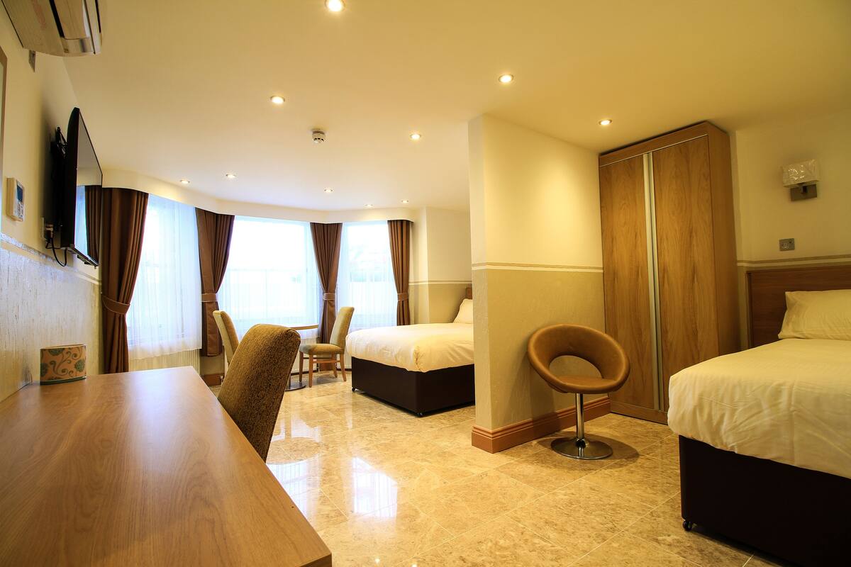 A hotel room with a bed, a desk, a chair, and a wardrobe.