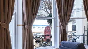 A hotel room with a bed, curtains, a view of the outside, and a sign reading "Duke Apart." - Arlo Apartments (Eastbourne)