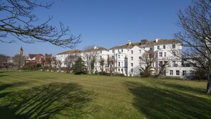 A row of white buildings with a church in the background. - Arlo Apartments (Eastbourne)