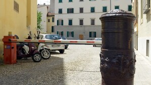 A cobblestone street with a parked scooter, a car, and a metal bollard. - La Terrazza Foscolo - con Parcheggio (Florence)