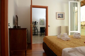 Une chambre d’hôtel avec un lit, une commode en bois, un bureau avec une chaise et une vue sur l’extérieur.