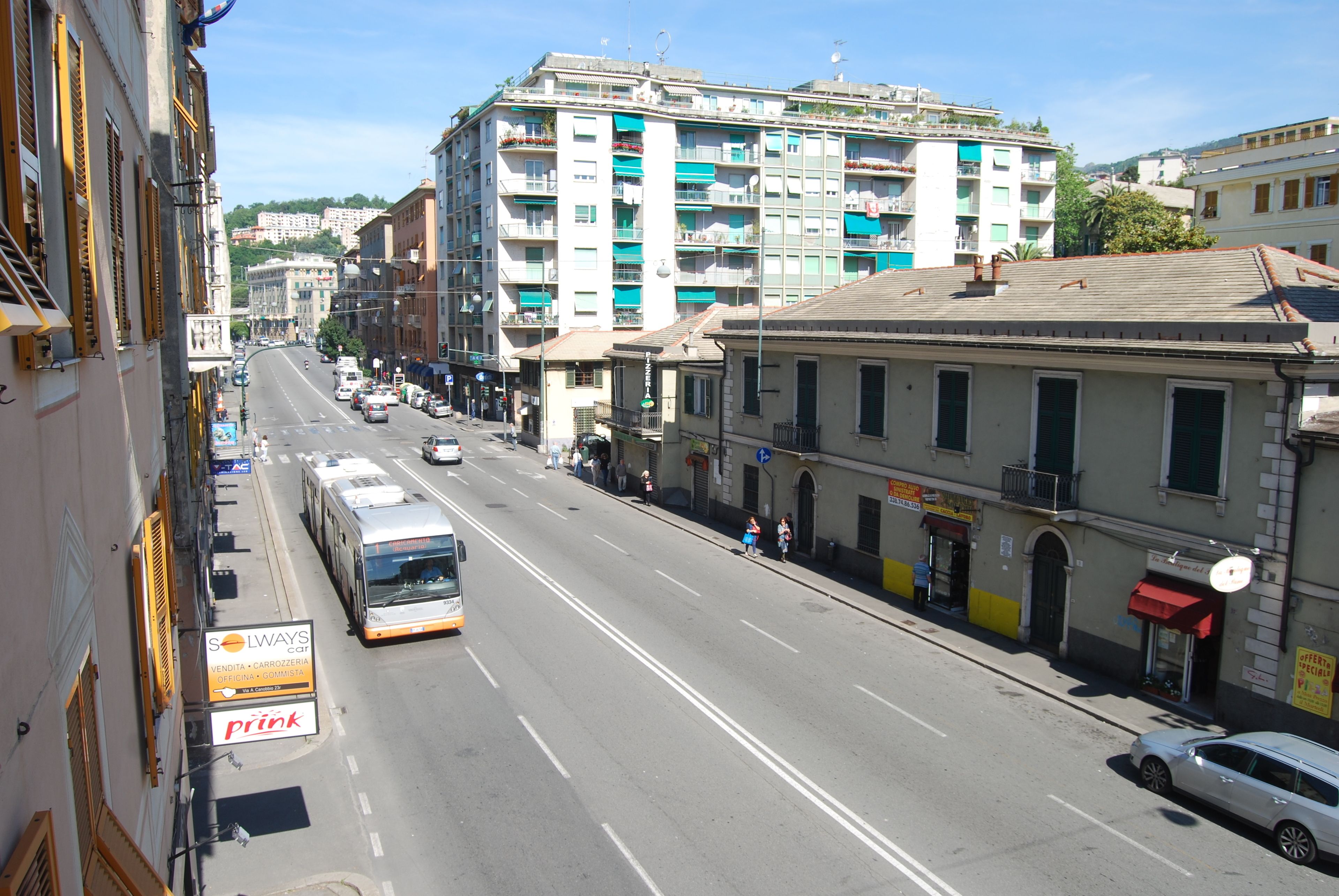 A street with a bus, buildings, and a sign for Solway's Carrozzeria.