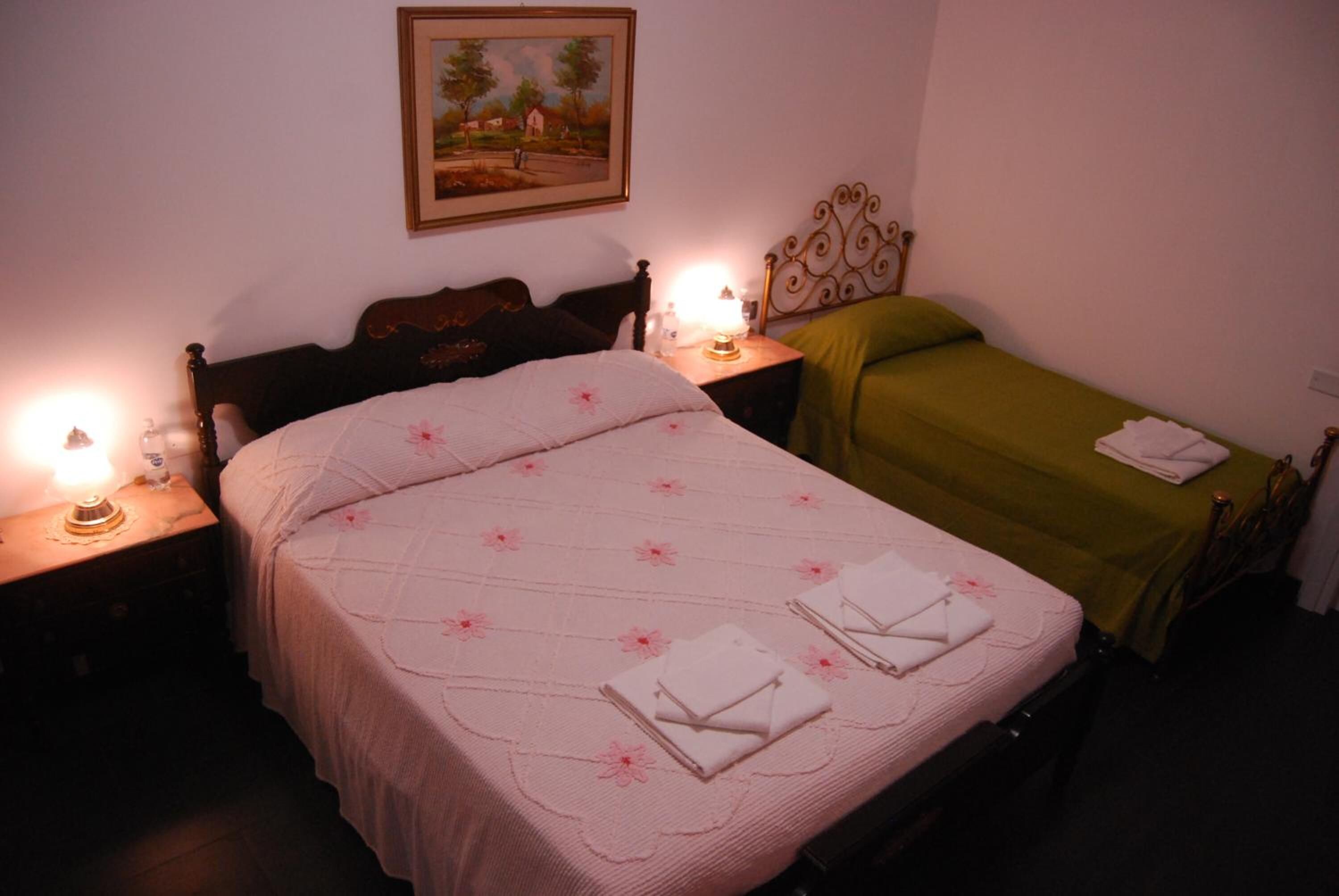 A bedroom with a large bed, two bedside tables with lamps, and a painting on the wall.