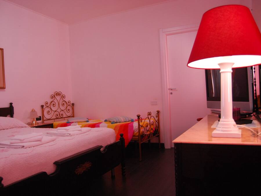 Ein Schlafzimmer mit Bett, Nachttisch, Lampe und Tür.