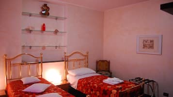 A bedroom with two single beds, a shelf with decorative items, and a framed picture on the wall.