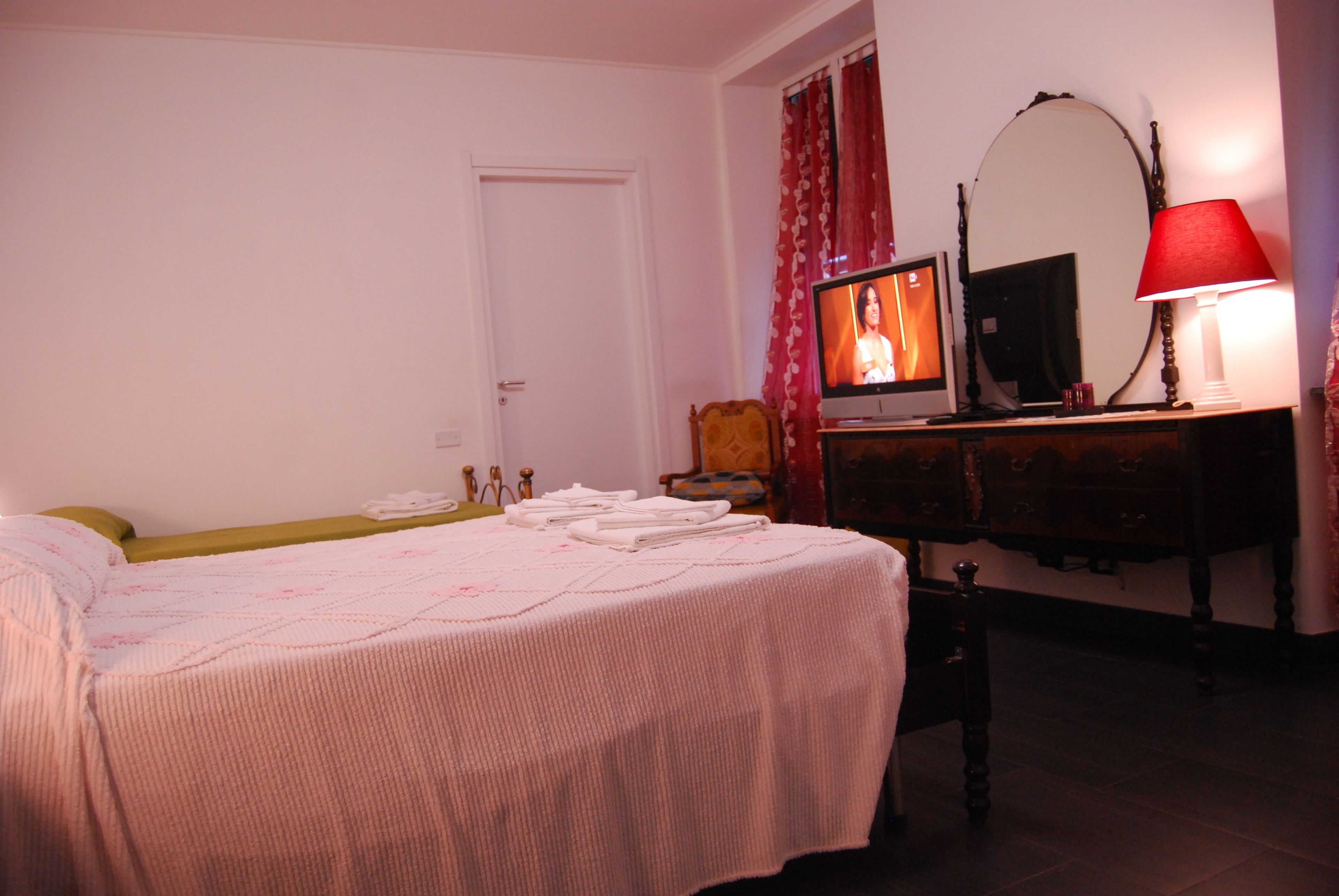 A bedroom with a bed, a television, a dresser, and a mirror.