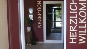 Una zona de recepción con una pared roja y un letrero que dice 'RECEPTION' y 'HERZLICH WILKOMMEN'.
