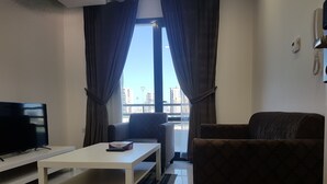A living room with a TV, a white coffee table, and a sofa. - Magic Suite Boulevard Salmiya (Salmiya)