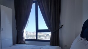 A bedroom with a large window, a bed, and a wardrobe. - Magic Suite Boulevard Salmiya (Salmiya)
