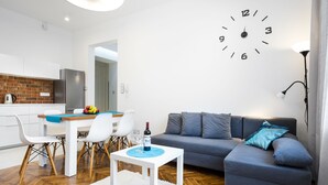 A modern living room with a grey sofa, a white coffee table, and a dining area with a table and chairs.