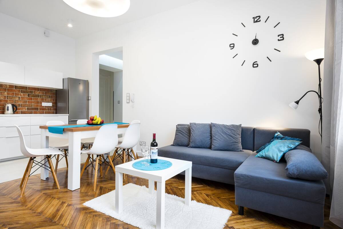 Ein modernes Wohnzimmer mit einem grauen Sofa, einem weißen Couchtisch und einem Essbereich mit Tisch und Stühlen.