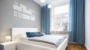 A modern bedroom with a bed, bedside table, and a motivational quote on the wall.