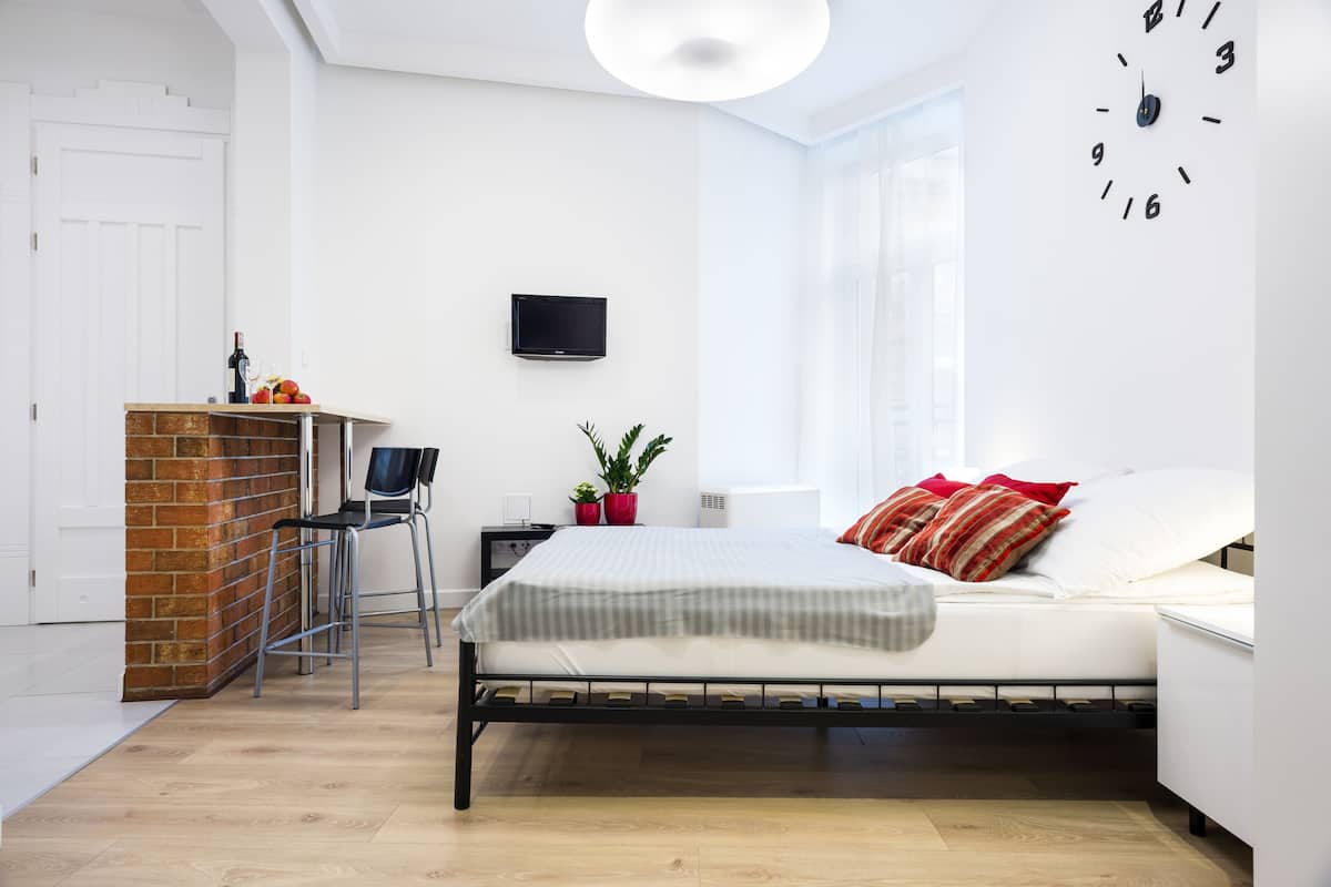 Ein modernes Schlafzimmer mit einem Bett, einem Fernseher, einem kleinen Schreibtisch und einem Fenster.