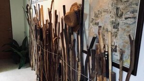 Een gang met een wandmontage van diverse houten gereedschappen en een ingelijste kaart.