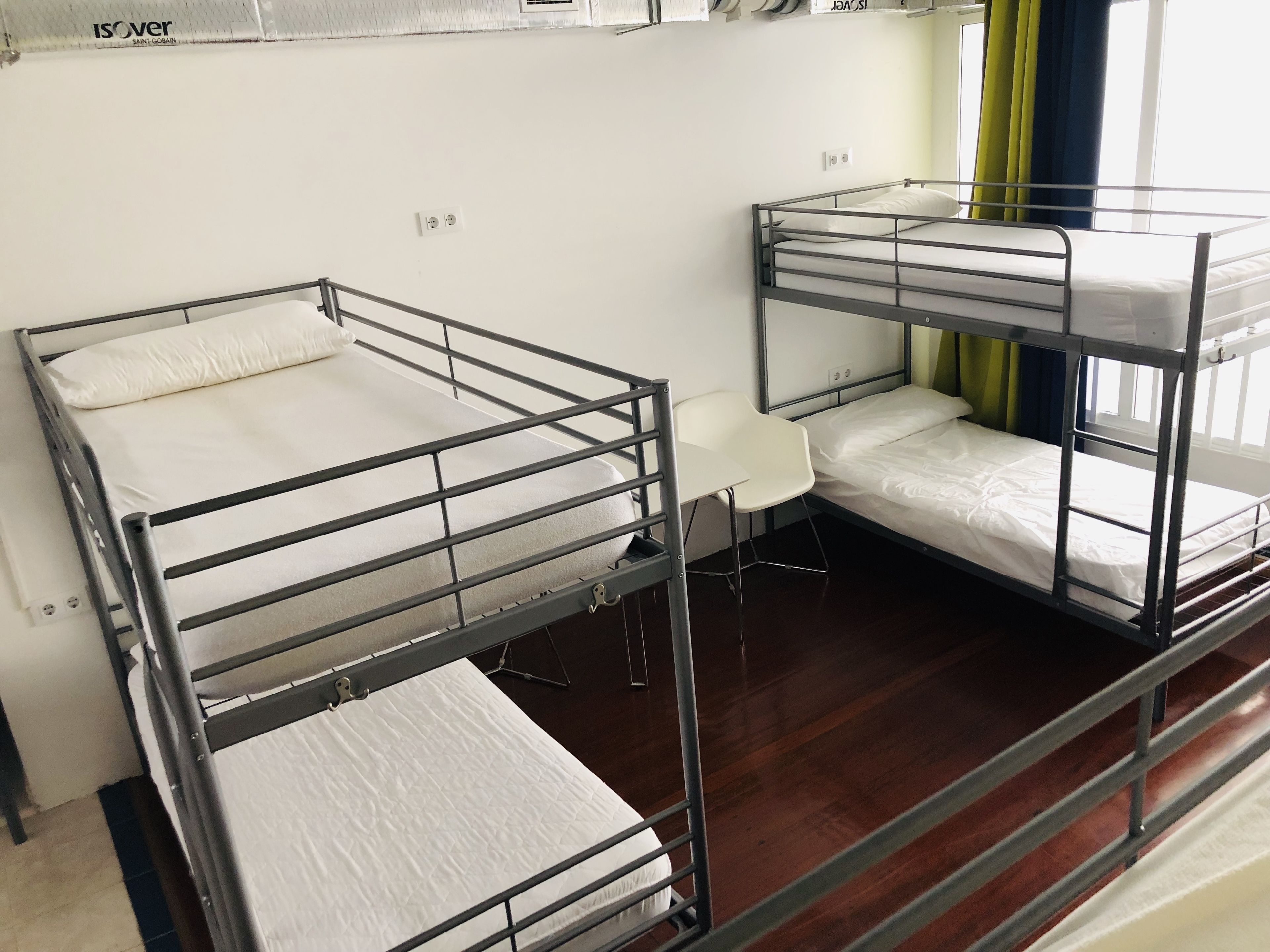 A dormitory room with bunk beds and a small desk.