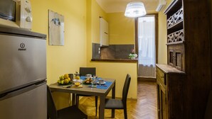 A compact kitchen with a refrigerator, a dining table with chairs, and a wooden cabinet. - Piccolo Sogno (Florence)