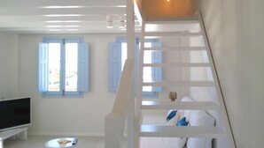 A modern interior with a staircase, a flat-screen TV, and a dining area. - Sol Mate Suites (Santorini)