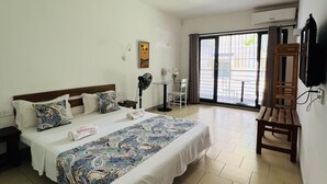 A bedroom with a large bed, a desk, a chair, and a TV mounted on the wall. - Hotel Ambatoloaka (Nosy Be)