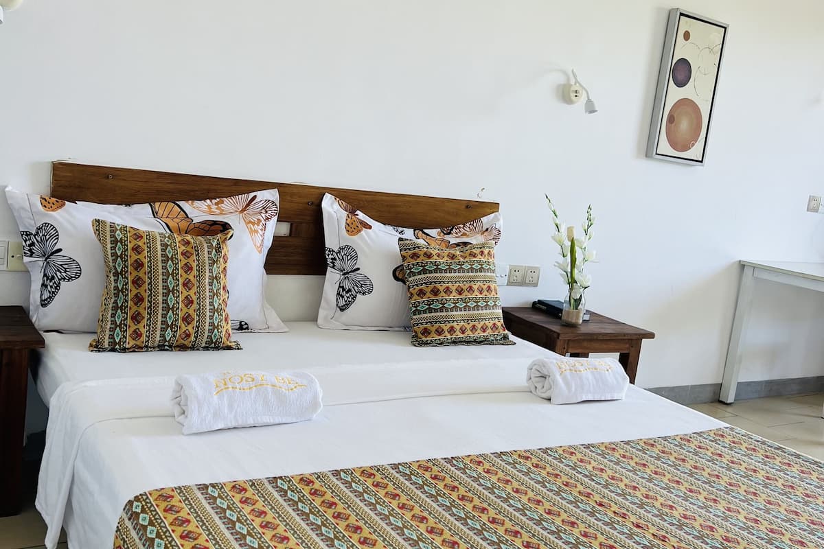Una cama bien hecha con almohadones estampados y un cabecero decorativo.