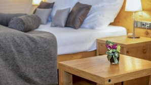 Habitación de hotel con una cama, una mesita de noche y una pequeña mesa con un arreglo floral.