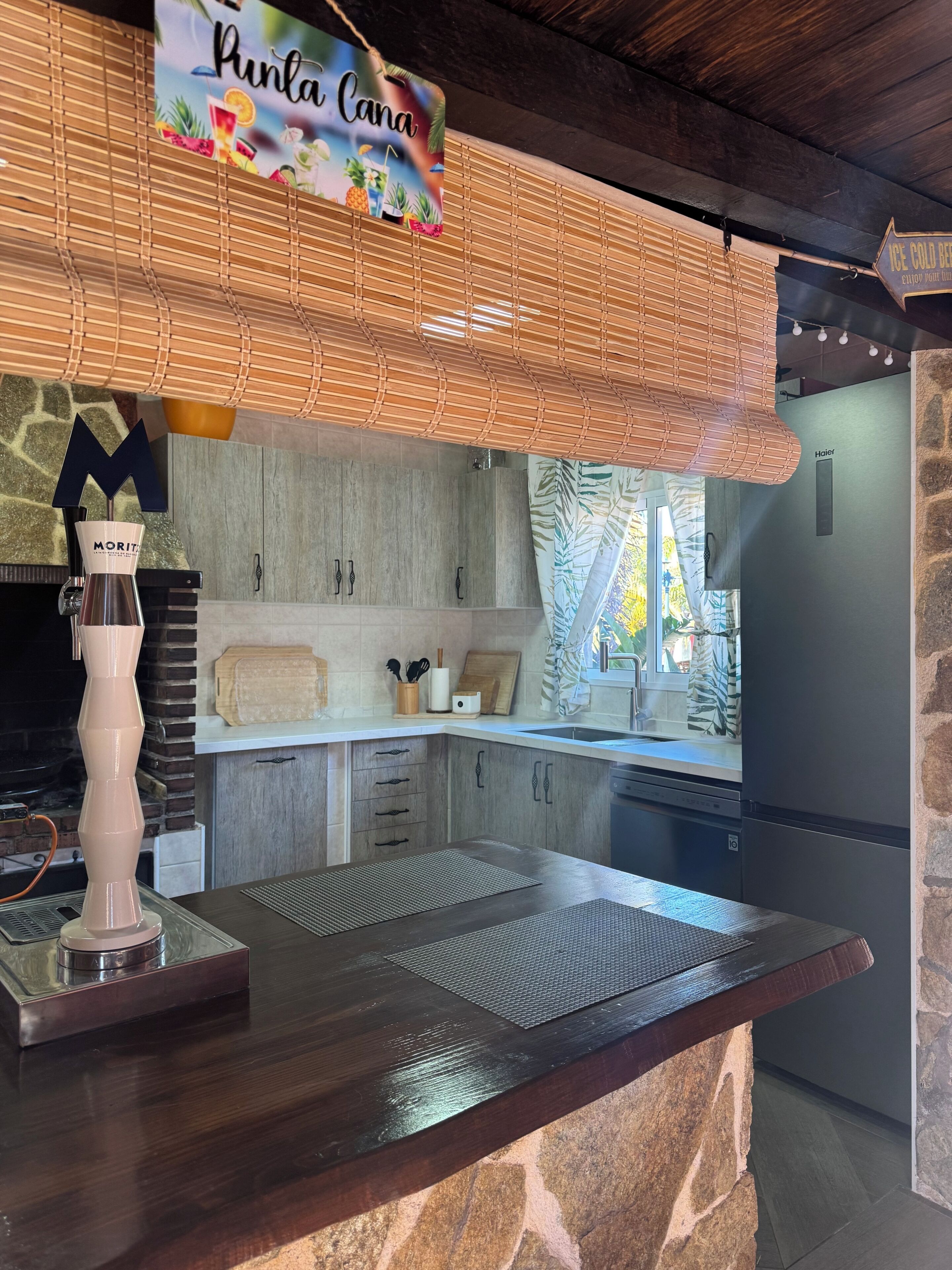 Une cuisine avec un mur en pierre, un plan de travail en bois, une machine à café Morit et une enseigne indiquant « Punta Cana ».