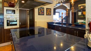 A modern kitchen with a black countertop, built-in ovens, and decorative items on shelves. - Owner Joan Andreu Calvet Fosch, Luxury villa with private pool. (Alcanar Playa)