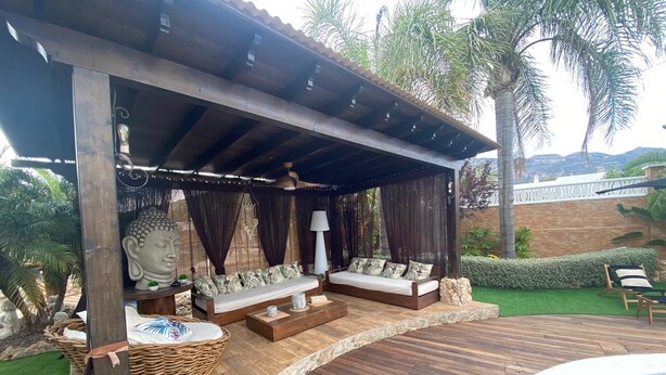 A covered outdoor seating area with a Buddha statue, wooden furniture, and a pool. - Owner Joan Andreu Calvet Fosch, Luxury villa with private pool. (Alcanar Playa)