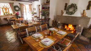 A dining area with wooden tables and benches, a fireplace, and decorative items.
