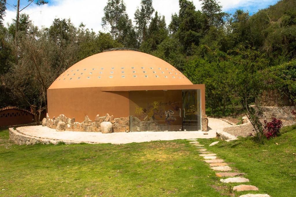 Un edificio de forma abovedada con un sendero de piedra que lo lleva a él, rodeado de follaje.