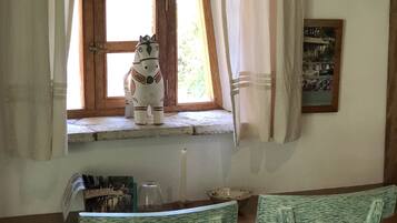Una habitación rústica con una ventana de madera, una figura decorativa de caballo, una vela y un cuadro en la pared.