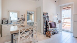 Een kamer met een houten bureau, een stoel, een boekenkast, een televisie en een koffer.