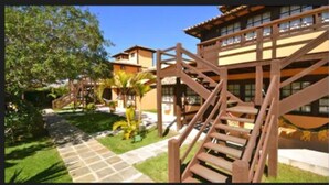 A hotel with multiple buildings, outdoor wooden staircases, and a paved pathway. - Da Ferradura (Búzios)