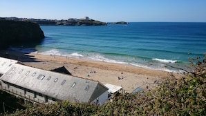 A beach with a view of the sea and a distant building on a hill.