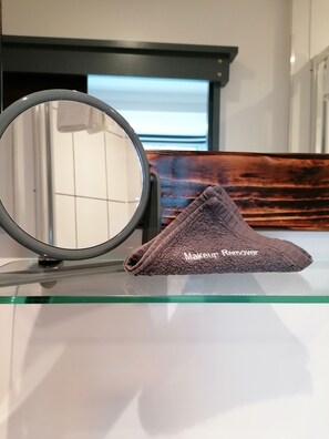 A bathroom with a round mirror, a glass shelf, and a brown towel labeled "Makeup Remover". - Pensalda Guest House (Newquay)