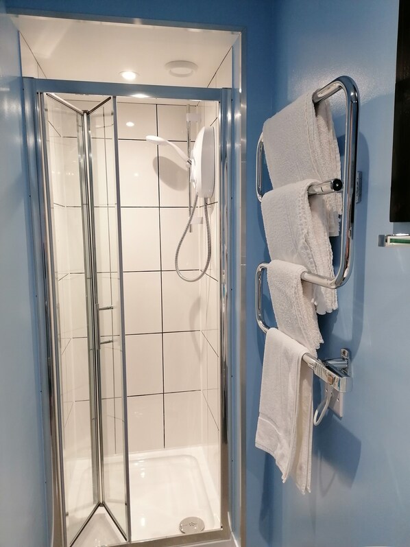 Un baño moderno con ducha de vidrio, paredes de azulejos blancos y una pared de acento azul.