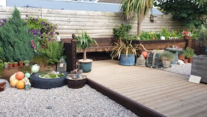 A garden with various plants, a wooden deck, and a sign that says "I love you to the moon and back."