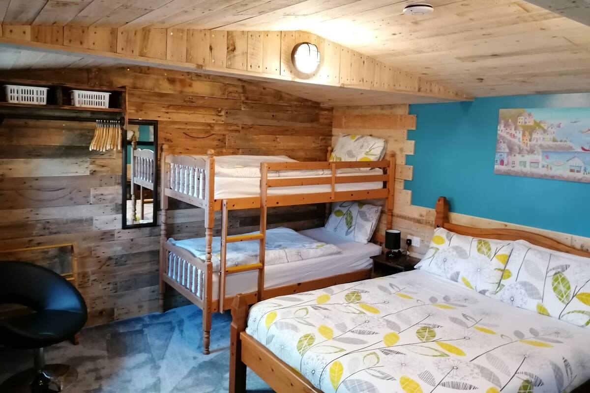 Une chambre avec des lits superposés, des murs en bois, un mur d’accent bleu et un tableau représentant une carte.